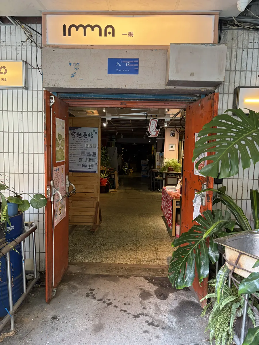 厭學避風港的入口，門口有招牌與綠色植物，走廊兩側是書架