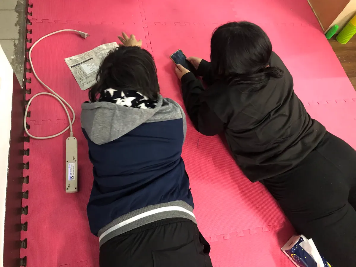 兩個人趴在軟墊上，一起看著手機